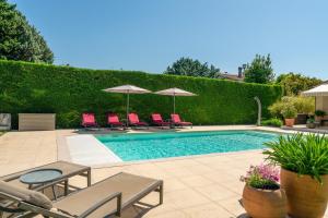 a swimming pool with red chairs and umbrellas at Chambre D'hôtes - Les Hirondelles in Mirabel-aux-Baronnies