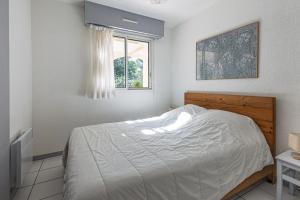 a white bedroom with a bed and a window at La Canopée - Conciergerieland in Soustons +17 photos