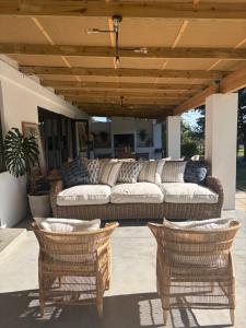 a couch on a patio with two wicker chairs at Bayerley in Plettenberg Bay