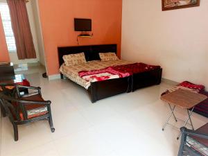 a bedroom with a bed and a tv on the wall at Stone Man's Hotel Samana Heights in Battakundi