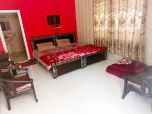a bedroom with a bed and a red wall at Stone Man's Hotel Samana Heights in Battakundi