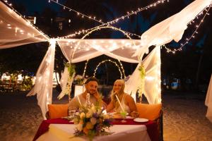 a man and woman sitting at a table under a tent at Beach Hot Dhigurah in Dhigurah