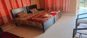 a bed with a red comforter on it in a bedroom at Stone Man's Hotel Samana Heights in Battakundi