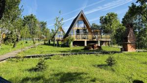a frame house with a thatched roof on a green field at Cozy A-Frame Cabin with Private Hot Tub - Chiang Mai in Şelari