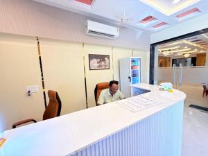 a man sitting at a counter in an office at Shri Gopal Durga Dham Hotel And Restaurant in Ujjain