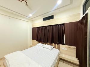 a bedroom with a white bed and a window at Shri Gopal Durga Dham Hotel And Restaurant in Ujjain