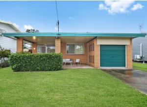 a house with a green garage door in a yard at Beach Side on Burke - Pet Friendly in Golden Beach