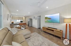 a living room with a couch and a television on a wall at Beach Side on Burke - Pet Friendly in Golden Beach