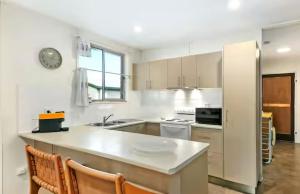a white kitchen with a counter and a refrigerator at Beach Side on Burke - Pet Friendly in Golden Beach +3 photos