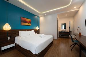 a bedroom with a large white bed and a desk at Flora Hoi An Lantern Town in Hoi An