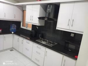 a kitchen with white cabinets and black counter tops at Margalla Hills View Apartment Islamabad in Islamabad
