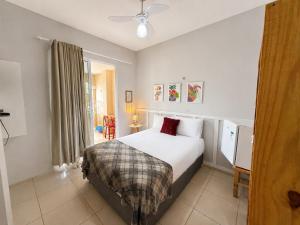 a bedroom with a bed with white sheets and red pillows at Hosts BR - La Serena Suíte Cumbuco in Caucaia