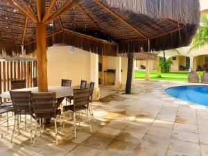 a patio with a table and chairs and a pool at Hosts BR - La Serena Suíte Cumbuco in Caucaia