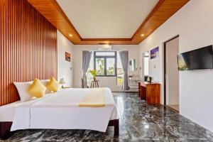 a bedroom with a large bed and a flat screen tv at Laughter Garden villas in Tân Thành (1)
