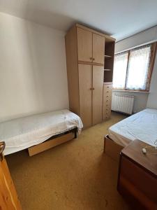 a bedroom with two beds and a cabinet and a window at Vecchio Mulino-Ceci's Flat in Entracque