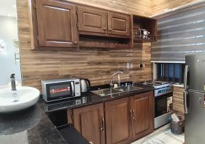 a kitchen with wooden cabinets and a sink and a microwave at Appartement Une Chambre Salon Ouando - SKYFORCE in Porto-Novo
