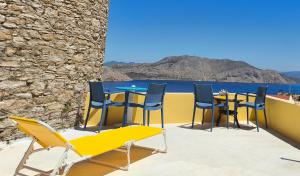 a patio with chairs and tables and a view of the ocean at The Mill House George in Symi