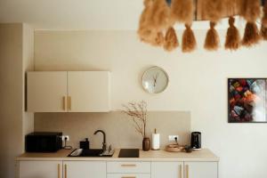 a kitchen with white cabinets and a clock on the wall at Kozia Chata - apartamenty nad rzeką in Brenna