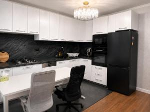 a kitchen with white cabinets and a black refrigerator at Spacious 3-Room Apartment - NEW Building in Bucharest