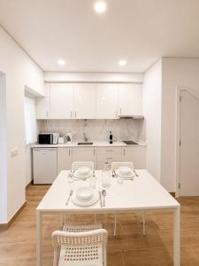 a white kitchen with a white table and chairs at Casa Rabiosa in Nazaré