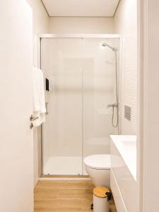 a white bathroom with a shower and a toilet at Casa Rabiosa in Nazaré +4 photos