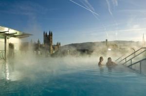 dos personas en un jacuzzi con un castillo en el fondo en The Paragon Townhouse en Bath