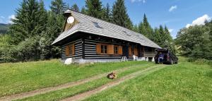 a dog sitting in front of a log cabin at Chata Telgart in Telgárt