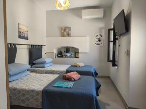 a room with three beds and a flat screen tv at The Mill House George in Symi