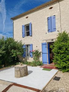 a house with blue shutters and a tree stump at Les Gîtes de Botte in Duras +24 photos