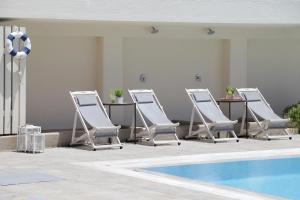 a row of lounge chairs and a swimming pool at Skopelos Village Hotel in Skopelos Town