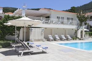 a pool with chairs and an umbrella next to a house at Skopelos Village Hotel in Skopelos Town