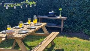 a wooden picnic table with glasses of wine on it at Vrijstaande bungalow met grote privé tuin dichtbij Veerse meer in Kortgene