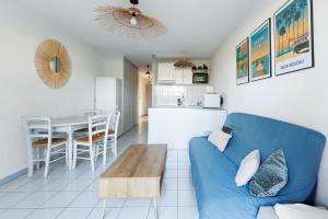 a living room with a blue couch and a table at La Canopée - Conciergerieland in Soustons