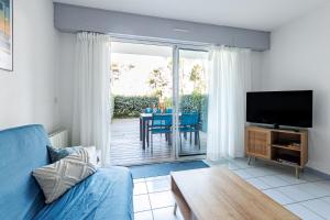 a living room with a blue couch and a television at La Canopée - Conciergerieland in Soustons