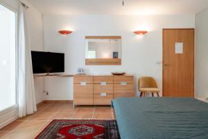 a bedroom with a bed and a dresser and a television at Chambre D'hôtes - Les Hirondelles in Mirabel-aux-Baronnies