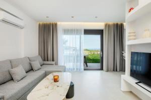 a living room with a couch and a tv at Adessa Villas in Afitos