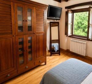 a bedroom with a large wooden cabinet and a television at La Senda del Norte in Cabezón de la Sal +8 photos