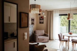 a kitchen and living room with a table and a chair at Kozia Chata - apartamenty nad rzeką in Brenna