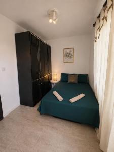 a bedroom with a green bed and a black cabinet at Apartman Dona in Petrovac na Moru