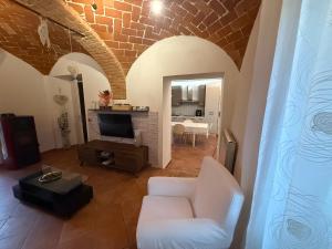 a living room with a white chair and a tv at Casa di Nina in Grazzano Badoglio