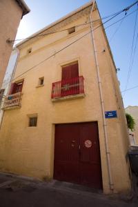 a building with a red door and a balcony at chez nous - la une in Marseillan
