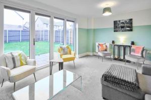 a living room with chairs and tables and windows at House Sleeps 8 with WiFi in Corby