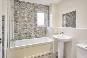 a bathroom with a bath tub and a sink at House Sleeps 8 with WiFi in Corby +26 photos