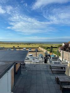a patio with picnic tables and cars in a parking lot at The Dormy House Hotel in Cromer