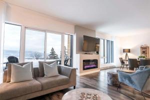 a living room with a couch and large windows at Chic Condo - River View & Comfort with Pool in Baie-Saint-Paul