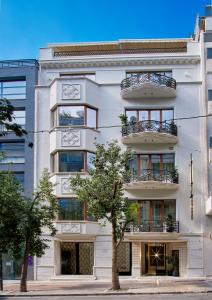 a white building with a tree in front of it at The Newel Kolonaki in Athens