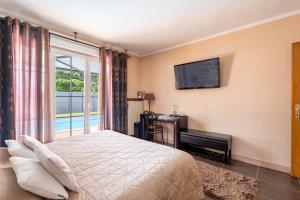 a bedroom with a bed and a tv and a window at Villa Béatrice - Piscine in Hochfelden