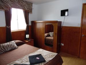 瓦尔帕莱索Hostal Tunquelen的一间带床和镜子的酒店房间