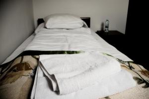 a bed with white sheets and towels on it at Pensjonat Korona in Modrzyca +45 photos
