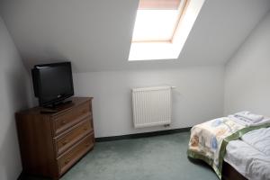 a bedroom with a bed and a tv on a dresser at Pensjonat Korona in Modrzyca